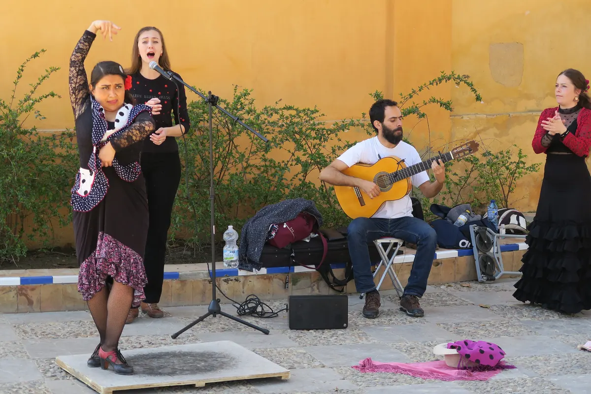 A flamenco dancer in a polka-dot shawl, a singer, a seated guitarist and a clapping palmera perform in a courtyard in Seville